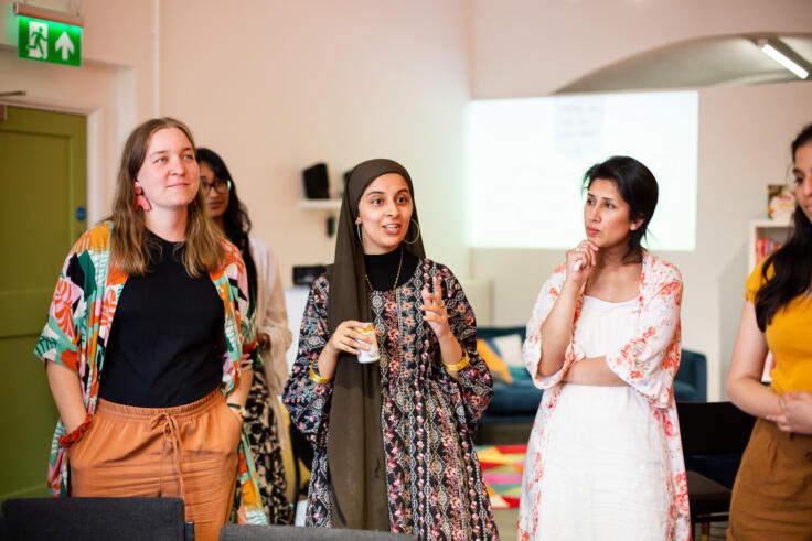 Four young women stand together in conversation.