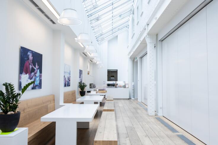 A long atrium in the Paul Hamlyn Foundation offices. The atrium is a high-ceilinged white room, with long bench seating and a sloping glass roof